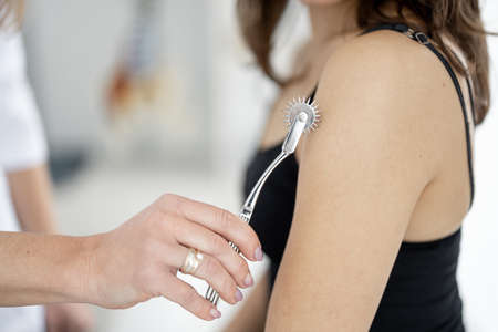 Neurologist makes skin reflex test with special instrument on a womens skin during medical appointment, close-upの写真素材