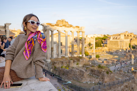 Portrait of a cheerful woman in front of the Roman Forum, ruins at the center of Rome on a sunset....