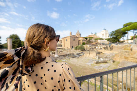 Woman enjoying view on the Roman Forum, ruins at the center of Rome. Concept traveling famous landmarks in Italy. Caucasian woman wearing dress and shawl in hairの写真素材