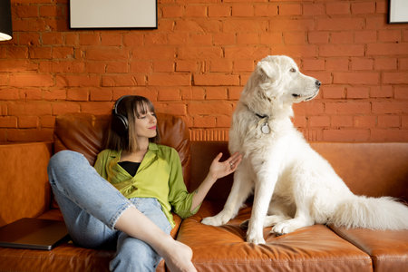 Young woman relax while sitting with her white adorable dog on a couch at home. Concept of...