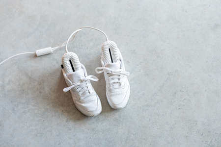 White sneakers drying with electric shoe dryer on the floor. Modern smart shoe dryer with timerの写真素材