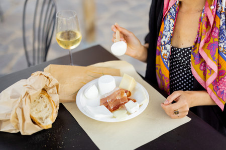 Woman tasting cheese and wine at local farm shop of Italy, close-up view on a plate. Concept of...