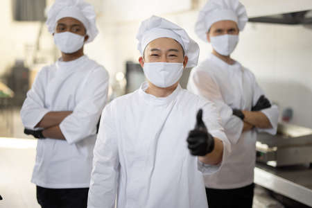 Portrait of chef cooks with different ethnicities standing together in restaurant kitchenの写真素材