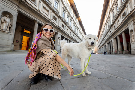 Young woman with a dog on Uffizi square visiting museum in famous italian city Florence. Female...