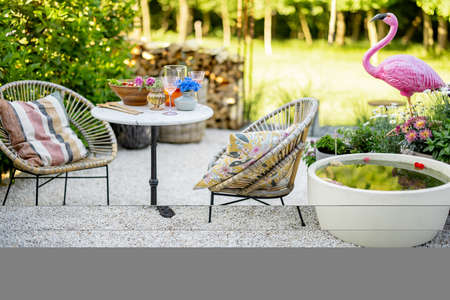 View on beautiful and cozy garden with coffee table, fountain and flamingo