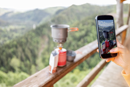 Traveler takes a picture of preparing food for hiking process, boiling water with a gas burner on...
