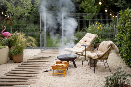 Atmospheric backyard with fire and lounge chairs at dusk on nature. Grilling food on fire bowl