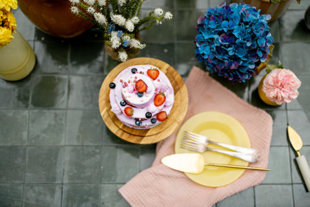 Beautiful tiled table served with festive berry cheesecake and decorated with flowers, view from...