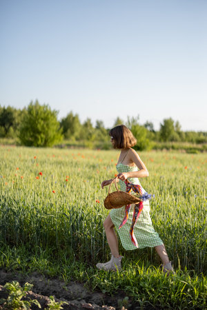Stylish woman in dress runs with wild flowers on field, spending summertime carefree on natureの写真素材