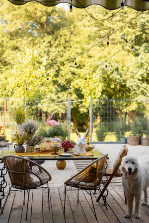 Beautiful and cozy dining place on wooden terrace at backyard. Cheese cake on garden table decorated with flowersの写真素材