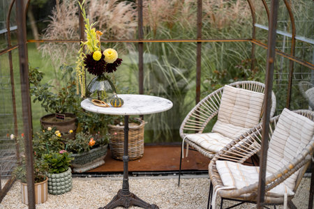 Beautiful bouquet of flowers in vase on the table in greenhouse with fogged up glass. Cozy place, floral conceptの写真素材