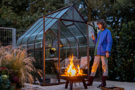 Woman spends leisure time having atmospheric evening picnic in the backyard with bonfire at dusk....
