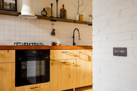 Stylish kitchen interior of modern apartment made in white and beige tones with wooden kitchen front and black kitchen appliancesの写真素材