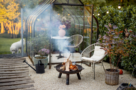 Beautiful and cozy garden with a picnic fire at lounge area and vintage greenhouse behind. Atmospheric and very beautiful courtyard of a country houseの写真素材