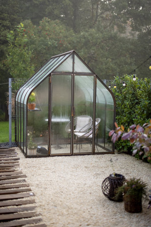 Morning view on backyard with beautiful vintage greenhouse in foggy weather. Tiny and cozy garden near forestの写真素材