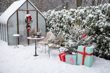 Beautifully decorated backyard with gift boxes, christmas tree and wreaths on winter holidays at snowy backyardの写真素材