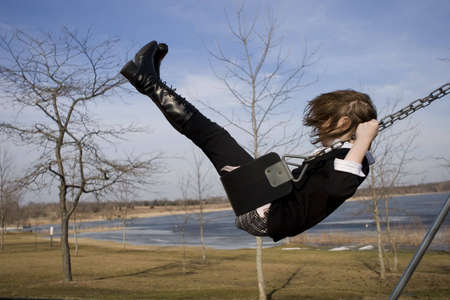 Girl on Swing in a park near a pondの写真素材