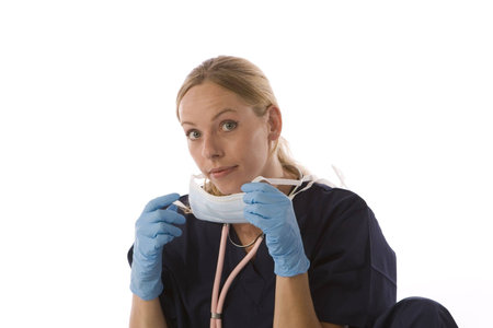 Young blond woman in medical scrubs with stethoscope and surgical mask