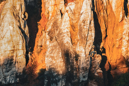 Climber clinging to the rock wall descending at sunset with his shadow reflected by the sunlightの写真素材