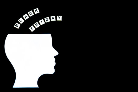 White silhouette of a human head with the words âBlack Fridayâ. The letters are arranged above the head, on a solid black background. This minimalistic composition emphasizes the concept of Black Friday, making it suitable for promotional or marketing purposesの写真素材