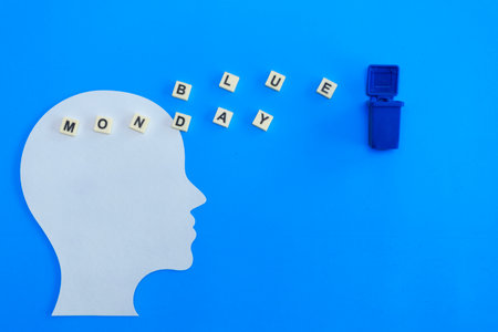 Silhouette of white human head, with letters forming âBlue Mondayâ towards a blue trash can. Composition on bright blue background. Concepts such as mental health, emotional well-being or marketing related to Blue Mondayの写真素材