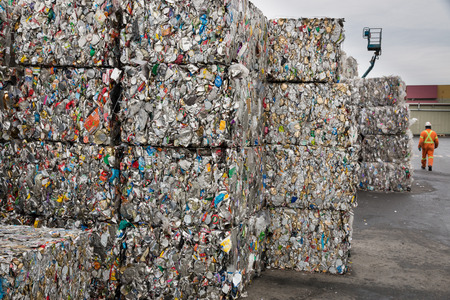 VICTORIA, CANADA- DECEMBER 11, 2013: An unidentified worker in the background, walks past cubes of crushed cans before they are shipped off to be melted down and made into new products.のeditorial素材