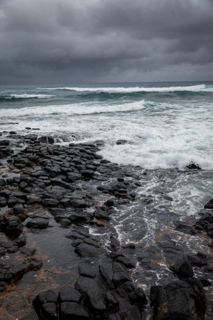 Stormy seas blow over a rocky volcanic shore in Kauai , Hawaii.