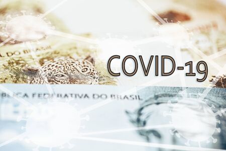 Brazilian money with the word COVID 19, macro and close up of 100 and 50 reais banknotes. Concept of problems in the Brazilian economy. Health crisis in Brazilの写真素材