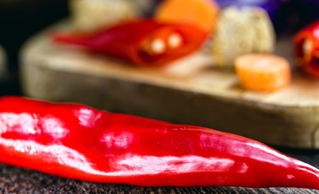 Red pepper and chopped vegetables, cut on wooden table, kitchen ingredients used in vegan food.