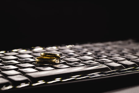 Concept of infidelity or virtual betrayal. Golden wedding rings on a personal computer keyboard.