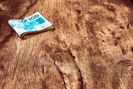 Brazil money notes and banknotes. Many one hundred brazilian real banknote, on a table. Spot focus on the table.の写真素材
