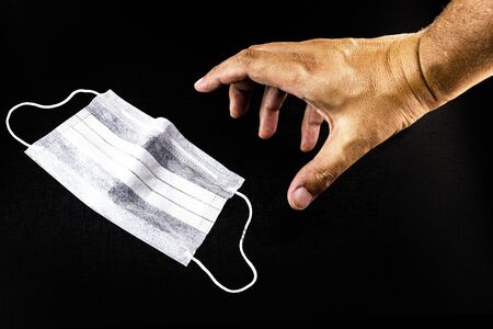 respiratory protection mask, on black isolated background, with hand. Quarantine, preventive social isolation.の写真素材