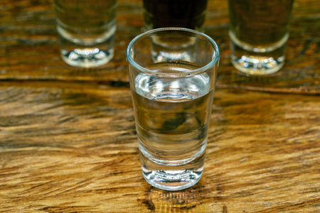 Several glasses of brazilian cachaÃ§a isolated on rustic wooden background, variations and types...