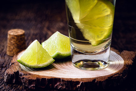 high quality distilled alcohol. Brazilian cachaÃ§a (called pinga) taken with lemon, drip, Russian vodka, white rum, vermont, soft tequila, ozo, sake or brandy. Drink on rustic wooden background.の写真素材