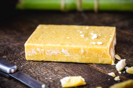 rapadura cut on rustic wooden table. Sugar cane candy, Brazilian dessert.の写真素材