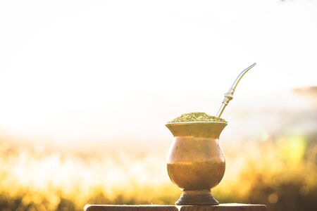 mate bowl, outdoors. Yerba mate typical of Argentina, Brazil and Uruguay. Mountain scenery in the background. It consists of a gourd, a pump, ground yerba mate and warm water.の写真素材