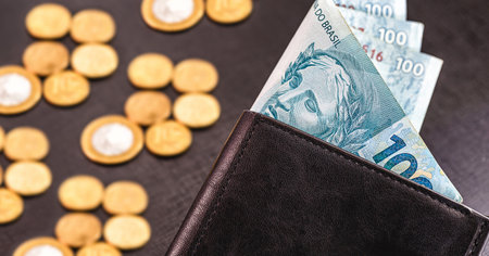 Banknotes of one hundred reais from Brazil in black leather wallet isolated on black background,...