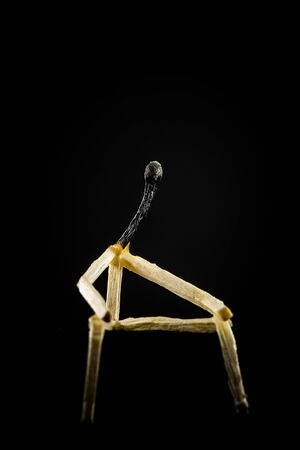 Concept of weakness or sadness. Image of a man made of matchstick. Small and depressive in the dark, erased and losing the flame.の写真素材
