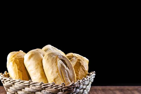 various traditional breads from brazil, on rustic wooden background in isolated straw basket. Space for text on black background. National day of Brazilian French bread.の写真素材
