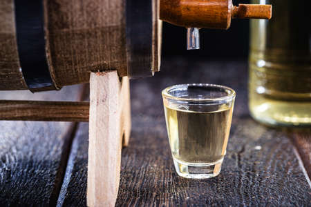 small dose glasses, high quality distilled alcohol. Brazilian cachaÃ§a (called pinga), dripping, with rustic wood brazil, bar image, old cellar.の写真素材