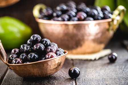 Jaboticaba or jabuticaba, Brazilian and South American fruit, in a copper pot on a rustic table....