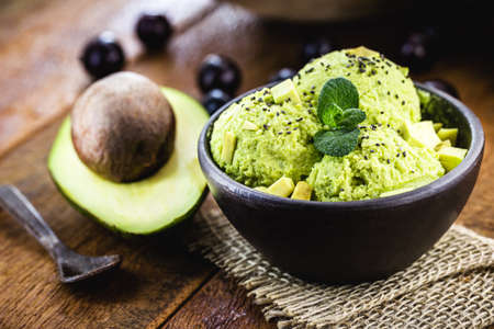 organic and natural avocado ice cream, without preservatives, with tropical fruits from brazil in the background, served in handmade clay bowl, gourmet ice creamの写真素材