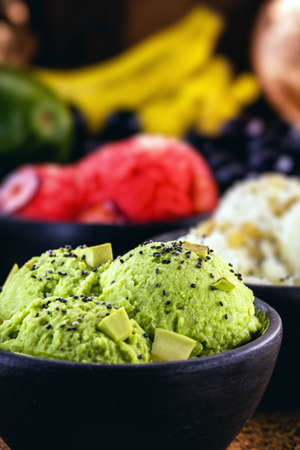 avocado vegan, banana and raspberry ice creams, without preservatives or added milk. With tropical fruits in the background, in handmade clay bowl.の写真素材