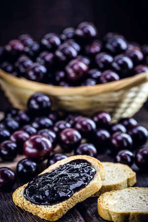 toast with grape jam, on rustic wooden table. Jabuticaba, exotic Brazilian fruit, used in cooking, as a sweet.の写真素材