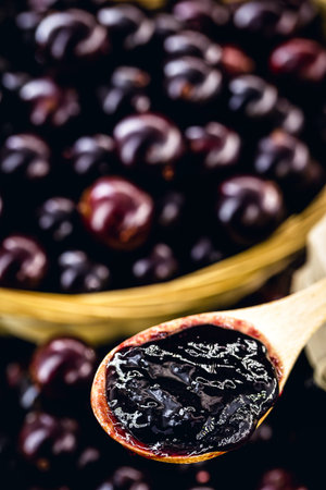 jabuticaba (or jaboticaba) jelly, close-up on wooden spoon, grape from latin america used in sweets...
