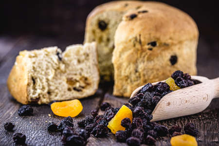 measuring wooden spoon with candied fruit, raisin and apricot, with panettone unfocused in the backgroundの写真素材