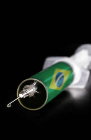 syringe or medical injection with flag of brazil on black background. Spot focus on the needle. Concept of crisis in Brazilian health due to covid - corona virusの写真素材