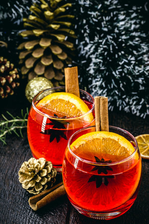 Mulled red wine with spices and Christmas fruits on a rustic wooden table with Christmas colors and lights. Traditional hot drink at Christmas timeの写真素材