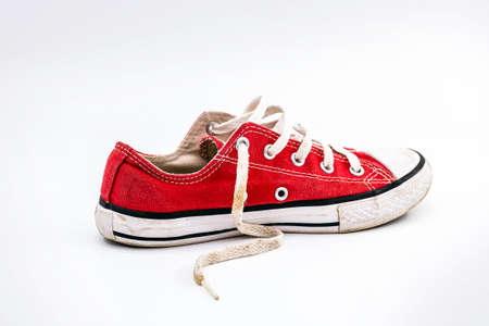 Side view of an old and dirty red sports shoe, made of elona, ââused and dirty. Old shoe concept, young lifestyleの写真素材
