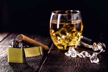 cigar on vintage lighter, with glass in the blurred background. Image with concept of masculinity, luxury and wealth, space for textの写真素材